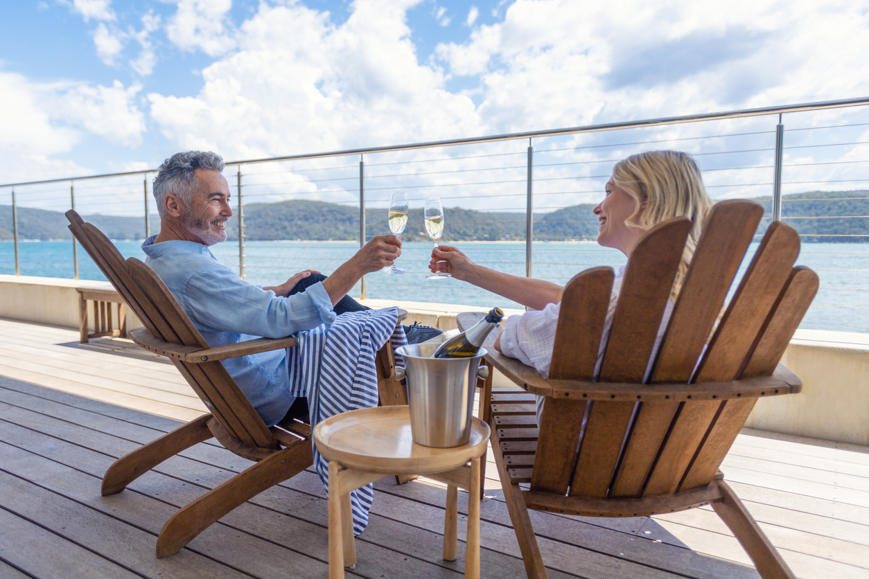 Investor couple relaxing on a waterfront deck of a property funded by an IUL policy loan